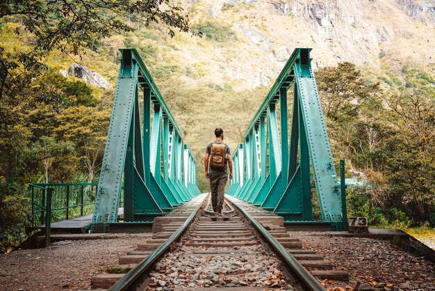 Uomo con zaino che cammina su un ponte verso la città di Machu Picchu