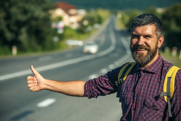 Uomo con zaino felice autostop su strada