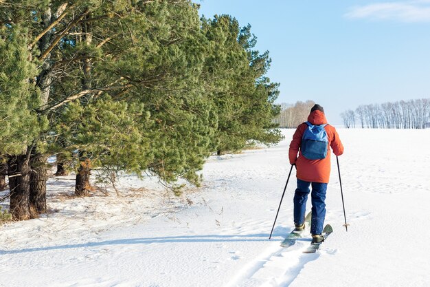 Uomo con zaino sugli sci sulla neve in una giornata invernale di sole. Libertà, stile di vita attivo, concetto di avventura.