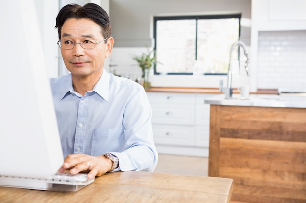 Uomo concentrato che per mezzo del computer a casa