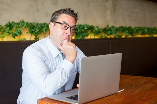 Uomo confuso di affari che lavora al computer portatile in caffè