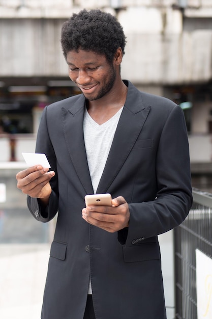 Uomo d'affari africano che utilizza smartphone e carta di credito per la transazione elettronica online