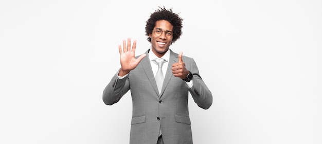 Uomo d'affari afro nero che sorride e sembra amichevole, mostra il numero sei o sesto con la mano in avanti, conto alla rovescia