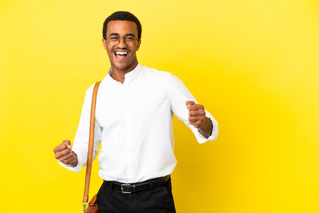 Uomo d'affari afroamericano su sfondo giallo isolato che celebra una vittoria