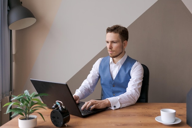 Uomo d'affari al lavoro Uomo che lavora al computer portatile mentre è seduto al tavolo di legno