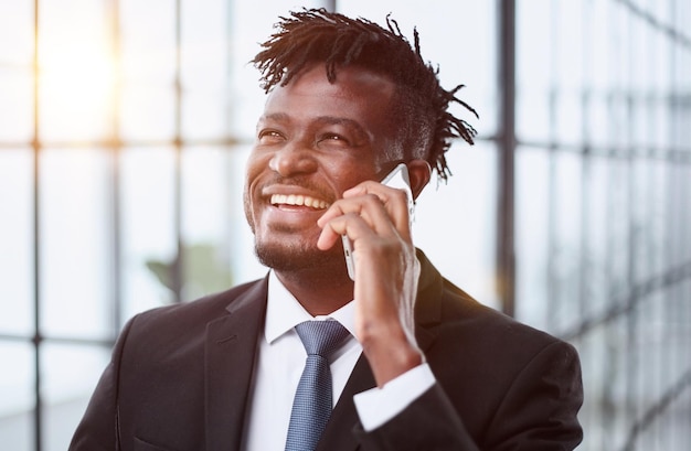 Uomo d'affari allegro e sorridente in un vestito che parla al telefono in ufficio