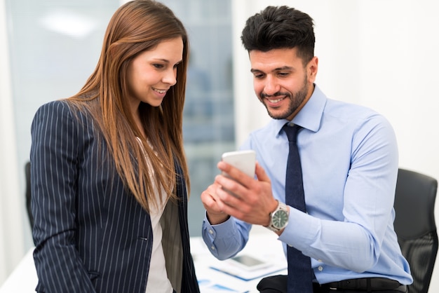 Uomo d&#39;affari amichevole che mostra lo smartphone ad un collega femminile nell&#39;ufficio