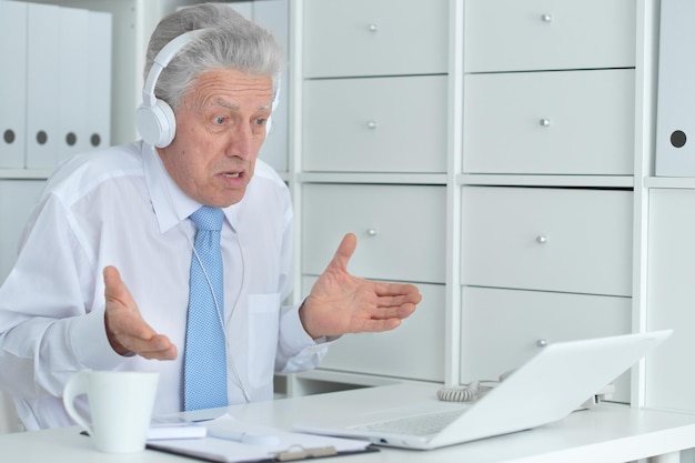 Uomo d'affari anziano che lavora in ufficio con un laptop