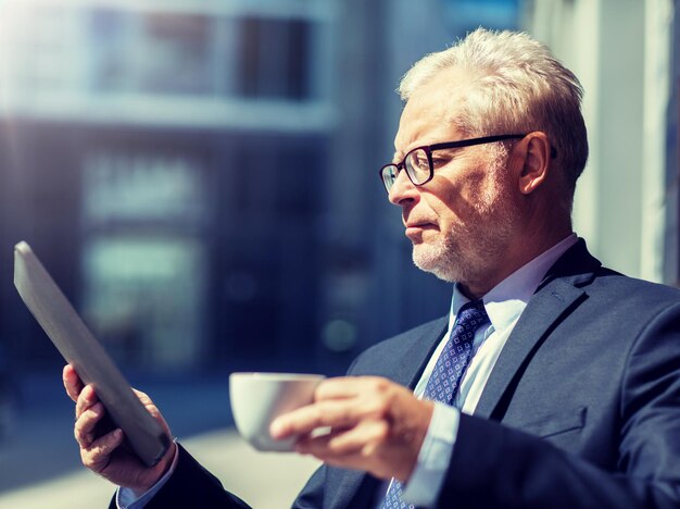 uomo d'affari anziano con un tablet che beve caffè