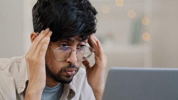 Uomo d'affari arabo malato studente capo capo barbuto maschio con occhiali ragazzo lavora con problemi con il laptop
