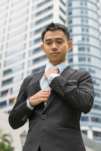 Uomo d'affari asiatico ben vestito che si aggiusta la cravatta?