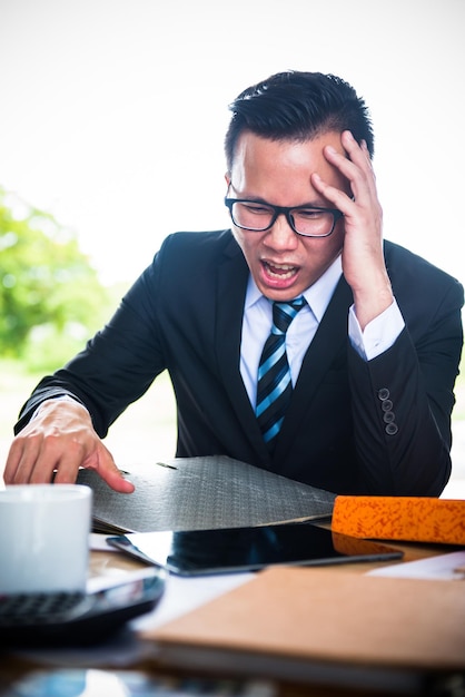 Uomo d'affari asiatico che lavora su tablet, costretto a lavorare e senza successo