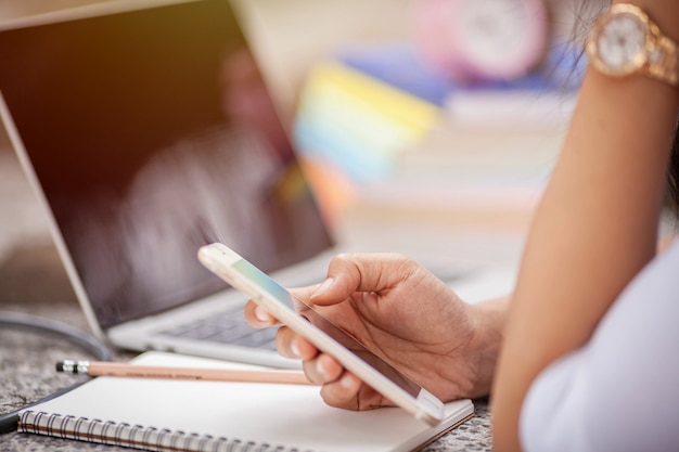 Uomo d'affari asiatico che per mezzo dello smartphone e del computer portatile al parco.