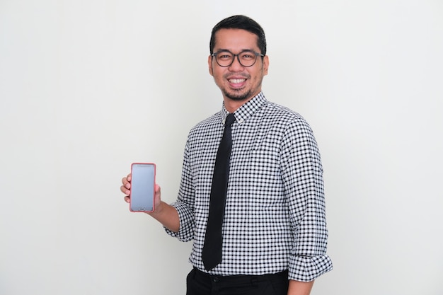 Uomo d'affari asiatico che sorride alla macchina fotografica mentre mostra lo schermo vuoto del telefono cellulare