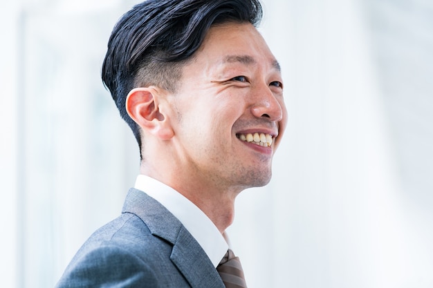 Uomo d'affari asiatico che sorride in uno spazio interno luminoso