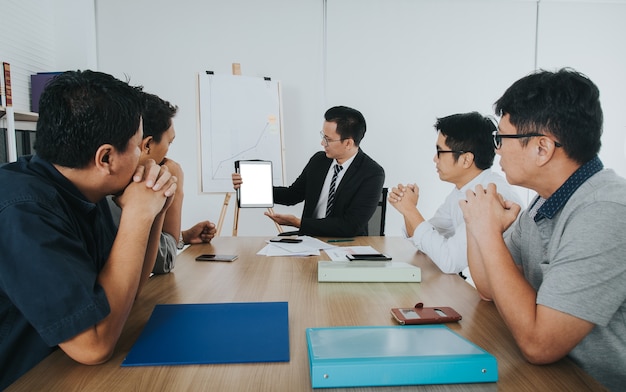 Uomo d&#39;affari asiatico che utilizza touchpad che discute alla sala riunioni.