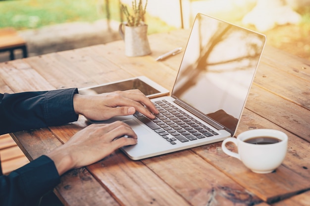 Uomo d&#39;affari asiatico con laptop sul tavolo in negozio di caffè con filtro d&#39;epoca tonica.