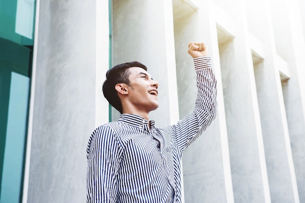 Uomo d&#39;affari asiatico di Happiness e di giovani in braccia sollevate nella posizione allegra da celebrare