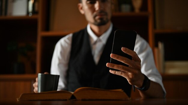 Uomo d'affari asiatico di successo che usa il suo smartphone alla scrivania dell'ufficio ritagliato