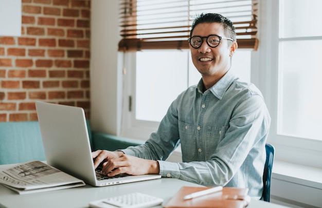 Uomo d'affari asiatico in un ufficio che usa un laptop