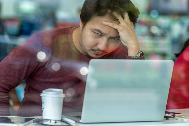 uomo d&#39;affari asiatico in vestito casuale facendo uso del computer portatile per lavorare