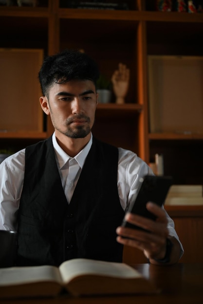 Uomo d'affari asiatico professionista o imprenditore maschio che utilizza uno smartphone alla scrivania