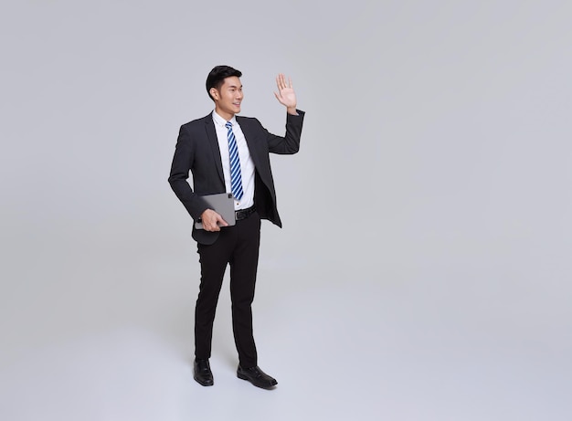 Uomo d'affari asiatico sorridendo sicuro camminando agitando la mano dire ciao saluto su sfondo bianco