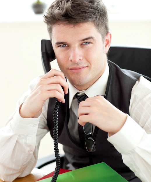 Uomo d&#39;affari attento che parla sul telefono che esamina la macchina fotografica