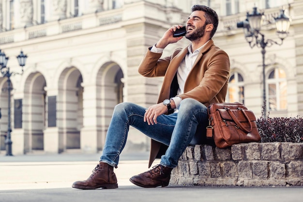 Uomo d'affari attraente che per mezzo del telefono astuto