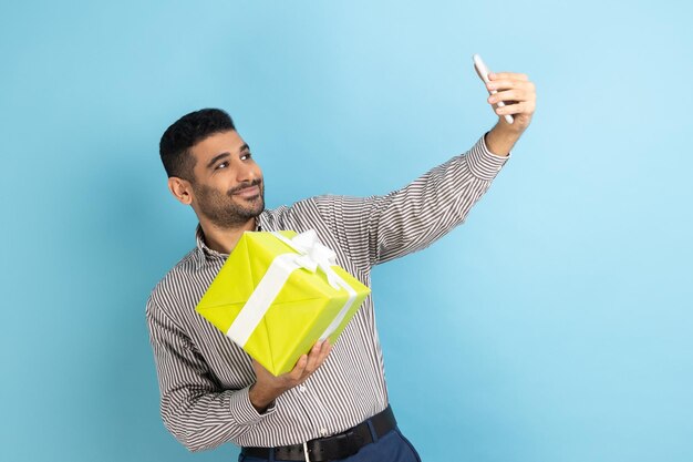 Uomo d'affari barbuto che fa selfie o registra video famoso blogger che prepara regali per gli abbonati