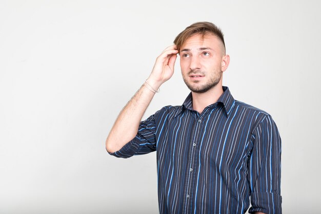 uomo d'affari barbuto con capelli biondi contro il muro bianco