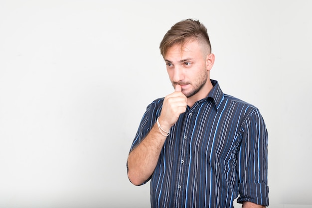 uomo d'affari barbuto con capelli biondi contro il muro bianco