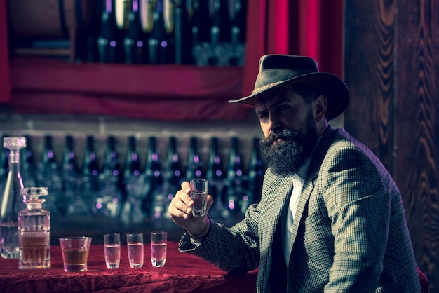 Uomo d'affari barbuto in abito elegante con bicchiere di whisky