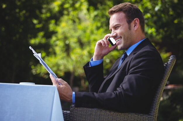 Uomo d'affari bello al telefono e leggendo il menu