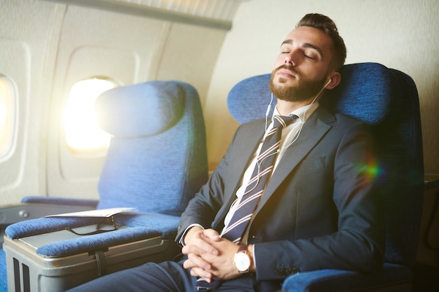 Uomo d'affari bello che dorme in aereo