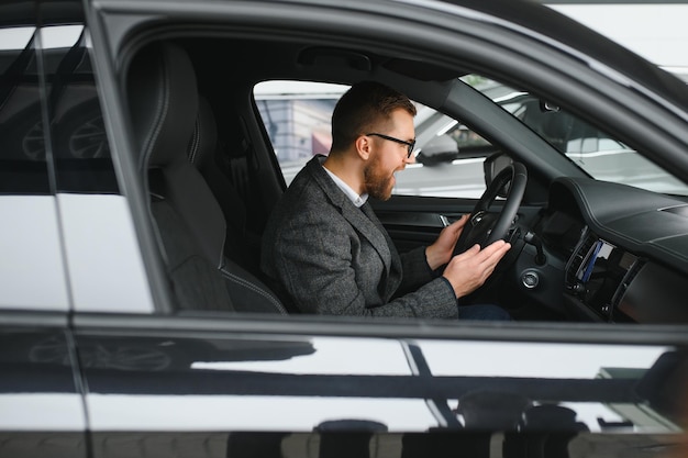 Uomo d'affari bello che guida automobile prima dell'acquisto