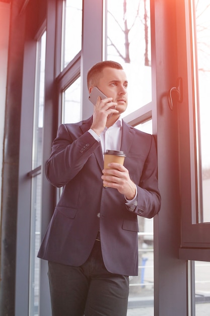 Uomo d'affari bello che indossa un vestito nero usando il telefono