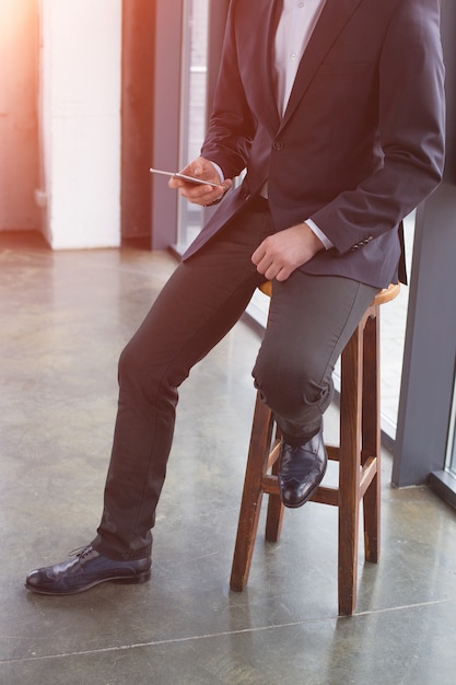 Uomo d'affari bello che indossa un vestito nero usando il telefono