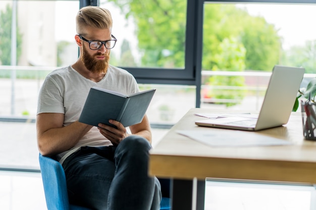 Uomo d'affari bello che lavora con il computer portatile in ufficio.