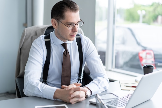 Uomo d'affari bello che lavora con il computer portatile in ufficio.