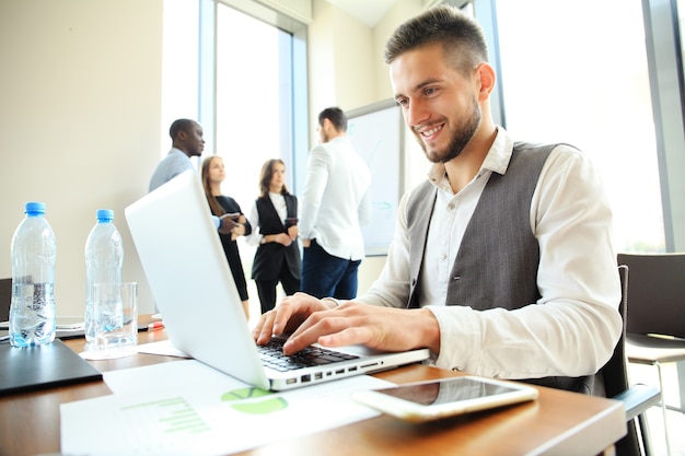 Uomo d'affari bello che lavora con il computer portatile in ufficio.