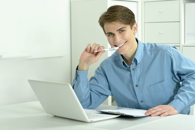 Uomo d'affari bello che lavora con il computer portatile in ufficio