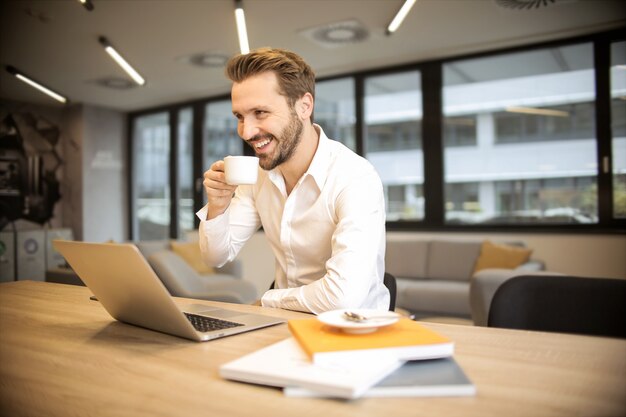 Uomo d&#39;affari bello che mangia un caffè