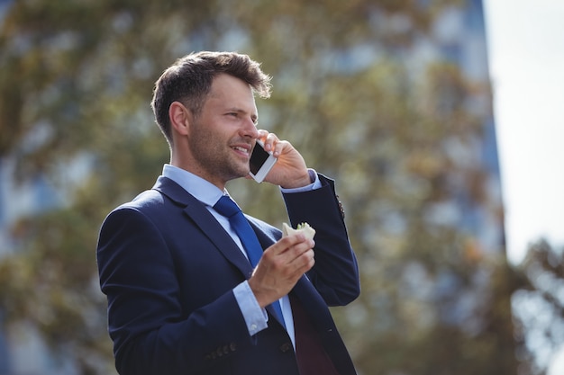 Uomo d'affari bello che parla sul telefono cellulare