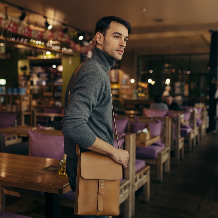 Uomo d'affari bello con la borsa di cuoio sulla sua spalla
