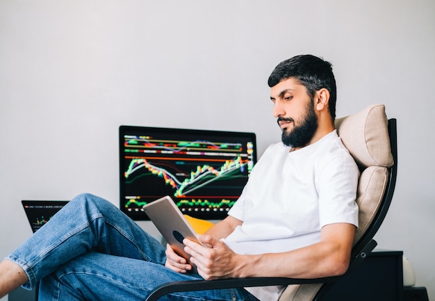 Uomo d'affari caucasico che commercia online, utilizza la tecnologia informatica, esamina il commercio di borsa e analizza
