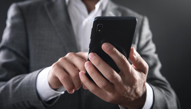 Uomo d'affari caucasico che utilizza smartphone in ufficio.