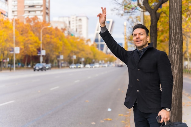 Uomo d'affari caucasico di mezza età che saluta un taxi alzando la mano per andare a lavorare sorridendo