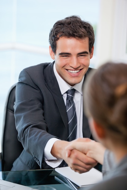 Uomo d&#39;affari che agita le mani con un cliente mentre sorridendo