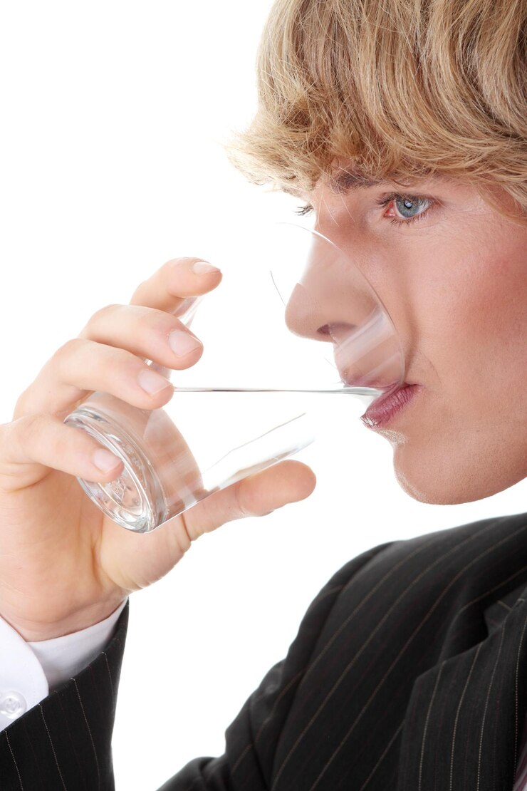 Foto uomo d'affari che beve acqua da un bicchiere su uno sfondo bianco